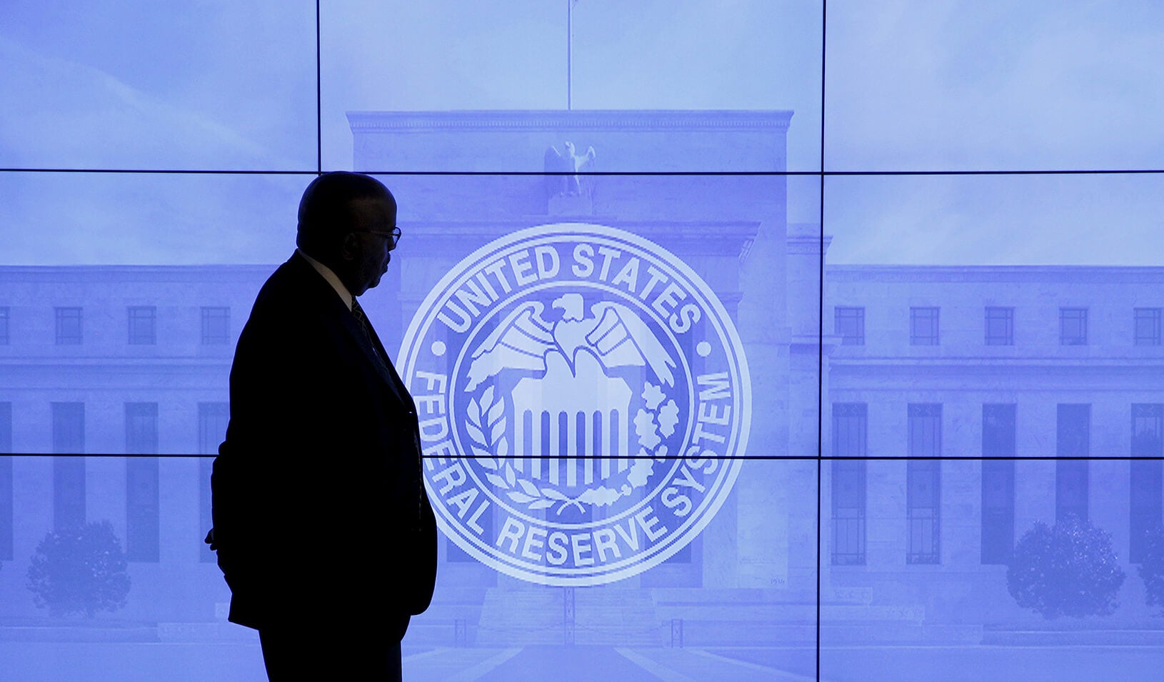 A man overlooks an emblem for the U.S. Federal Reserve System | Reuters/Kevin Lamarque