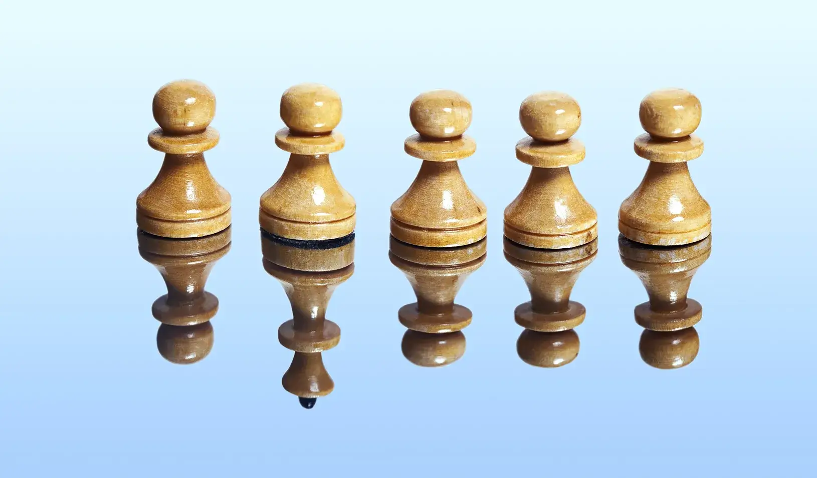 A photo-illustration showing a row of chess pawns, but in the reflective surface they sit on, you can see that one is really the queen. Credit: iStock/nikamata