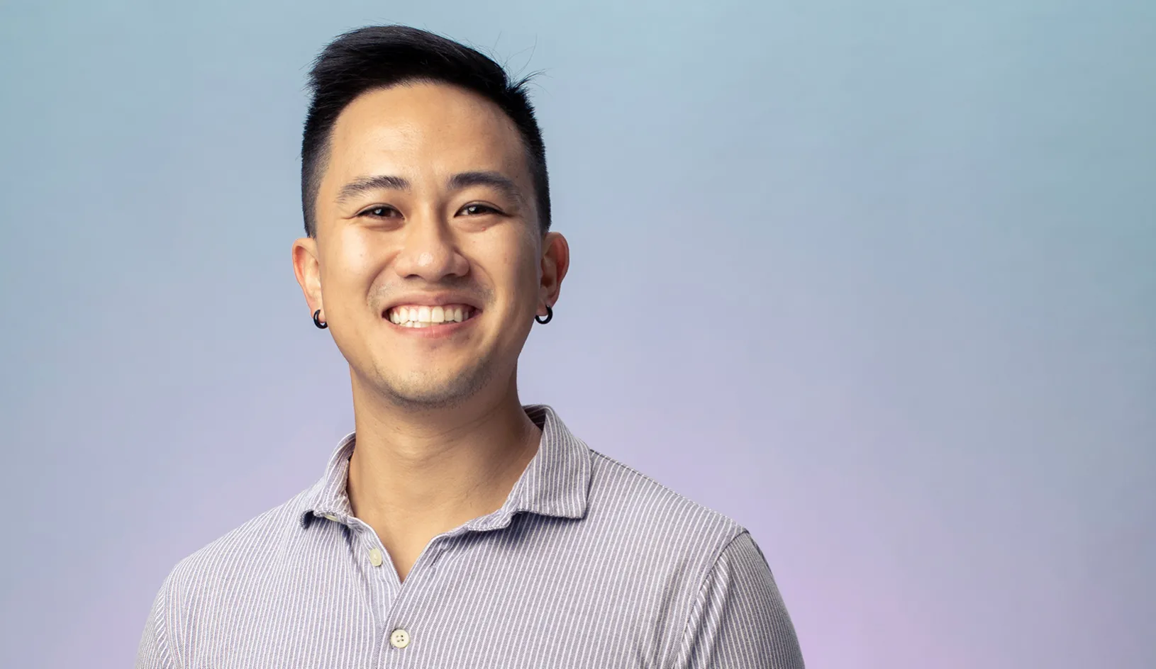 MBA 2022 student Viet Nguyen laughing and looking into the camera on a bright and colorful background. | Credit:  Elena Zhukova.