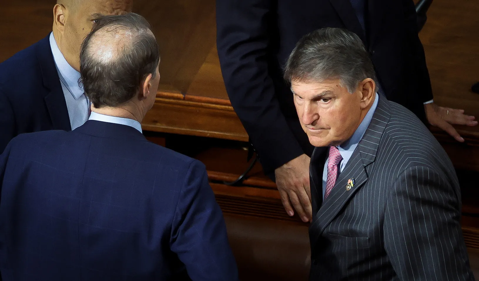 Senator Joe Manchin looks to his left while standing in a group with other lawmakers.