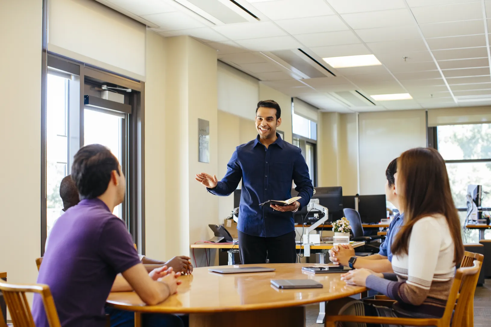 A GSB student presenting to fellow students around a table