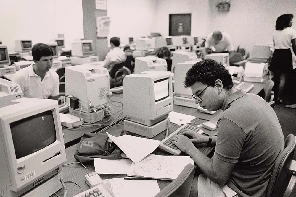 Historical black and white image from the GSB archives, showing someone working in a computer lab.