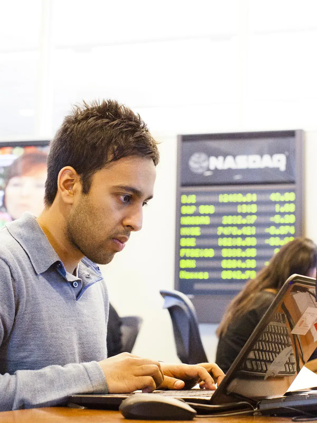 Student in a classroom with a NASDAQ in the background