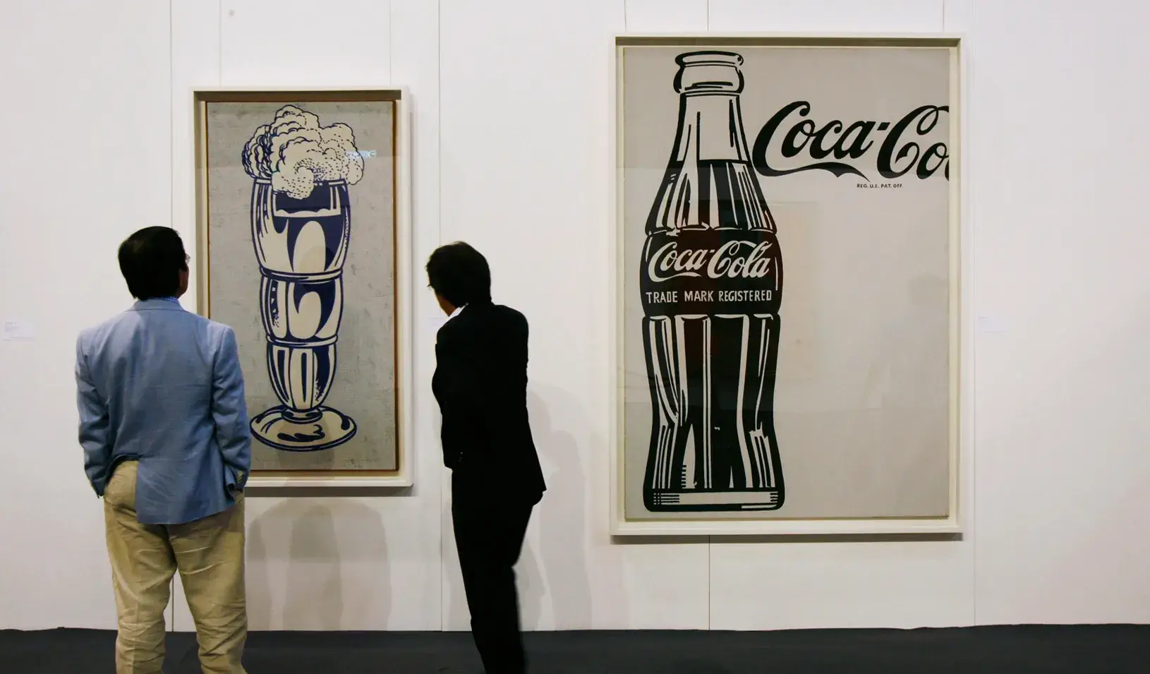 People view the artworks "Coca-Cola" (R) by Andy Warhol, and "Ice Cream Soda," by Roy Lichtenstein, on display at the Sotheby's Autumn Sales in Hong Kong.