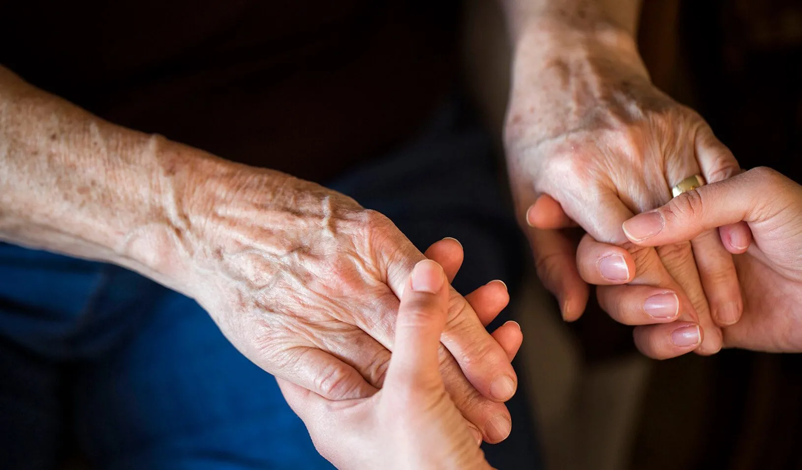 A young woman holds an older woman’s hands | iStock/Xesal