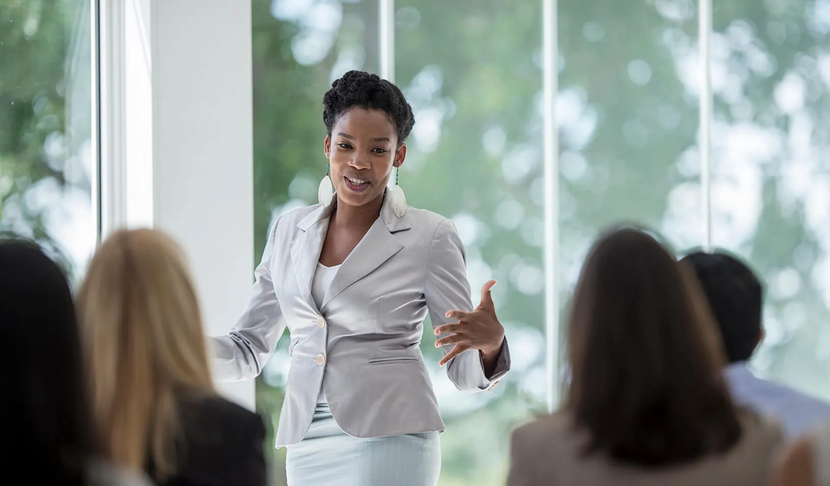 A woman speaking in front of a room of people. | iStock/FatCamera