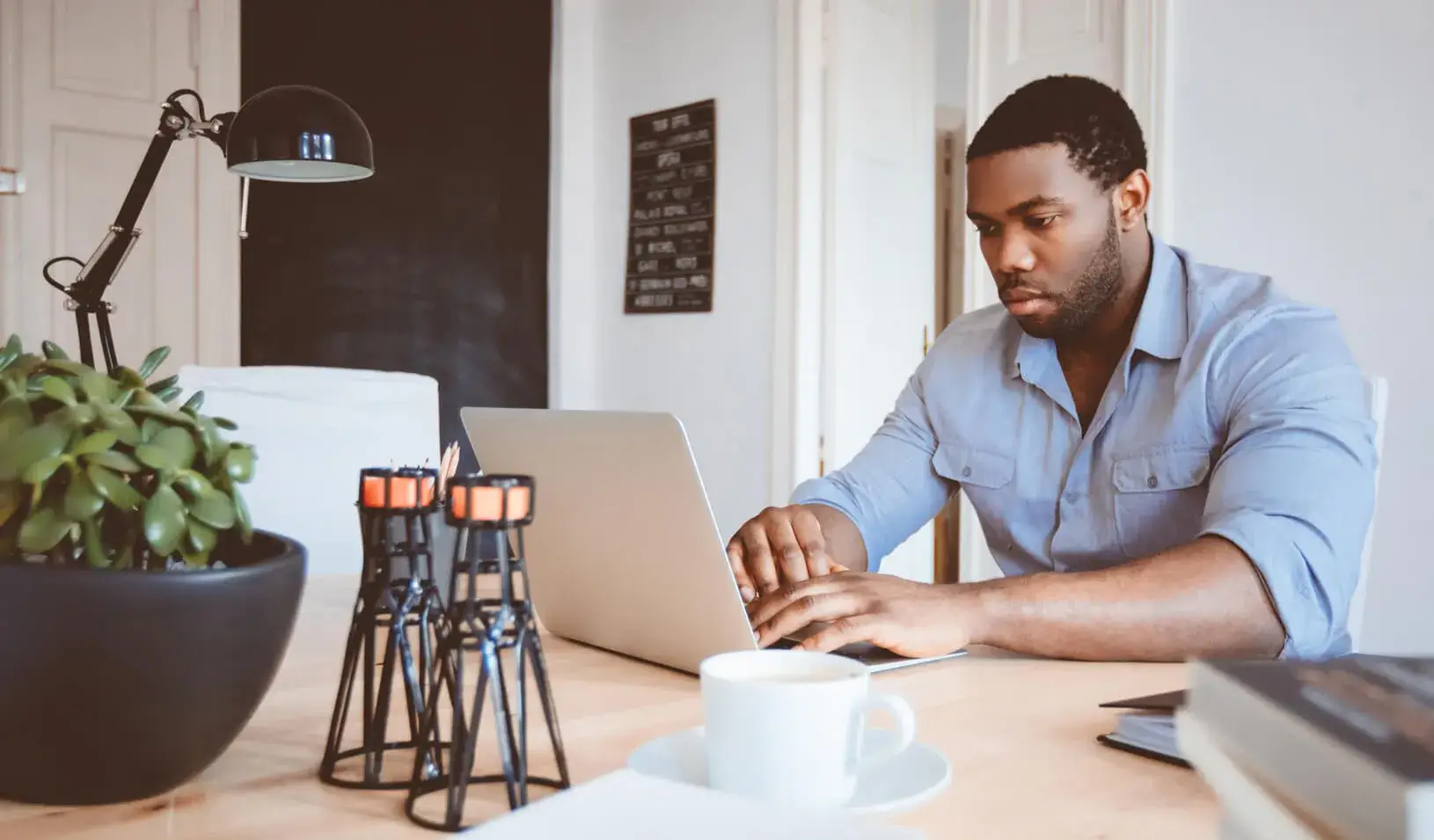 A man works at a computer in his home office, Credit: iStock/izusek
