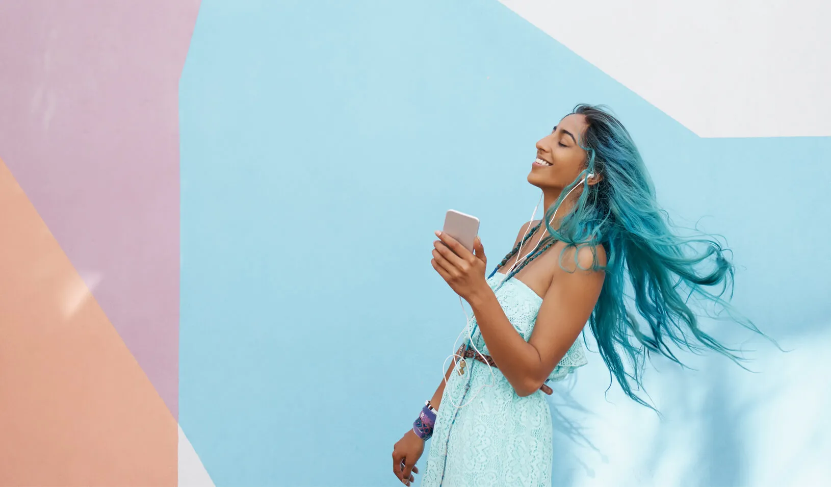 A woman smiles and dances as she listens to music | iStock/NKS_Imagery