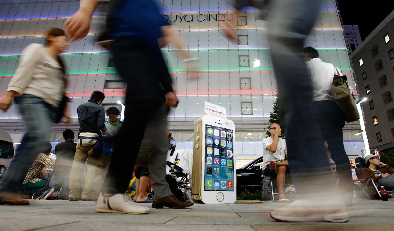 People sit next to a cardboard depicting Apple's new iPhone 5S in Tokyo, 2013 (Reuters photo by Toru Hanai)
