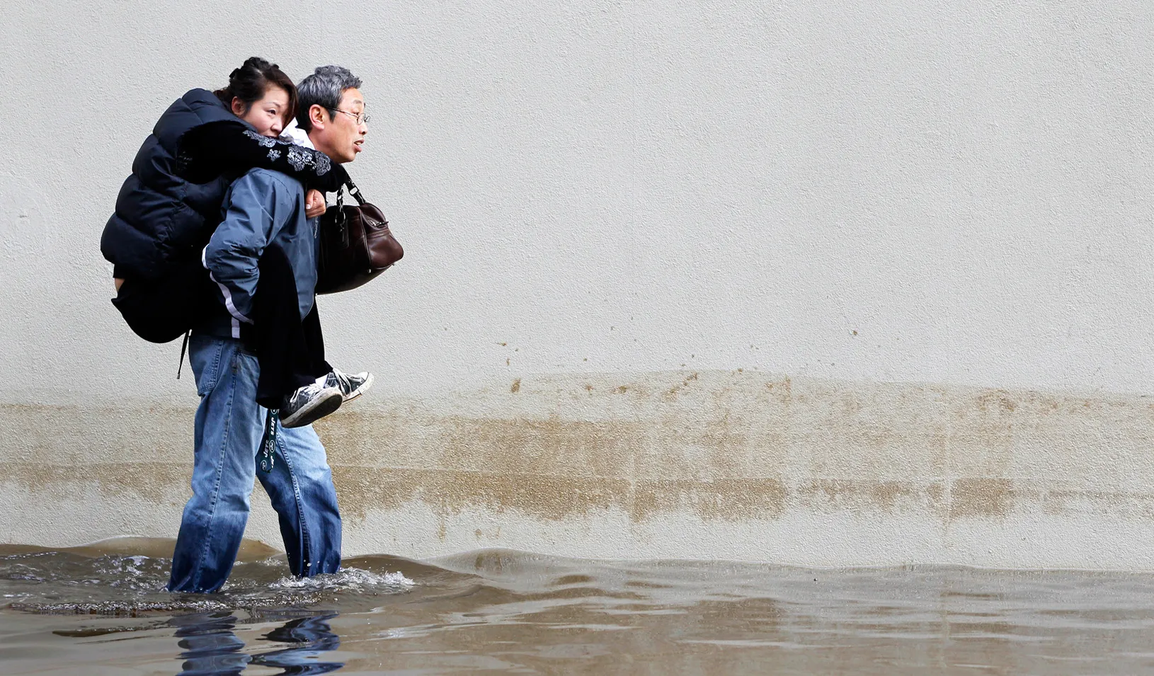 A man carries his wife through the floodwaters in Hoboken, N.J. after the 2012 monster storm Sandy. (Reuters photo by Gary Hershorn)