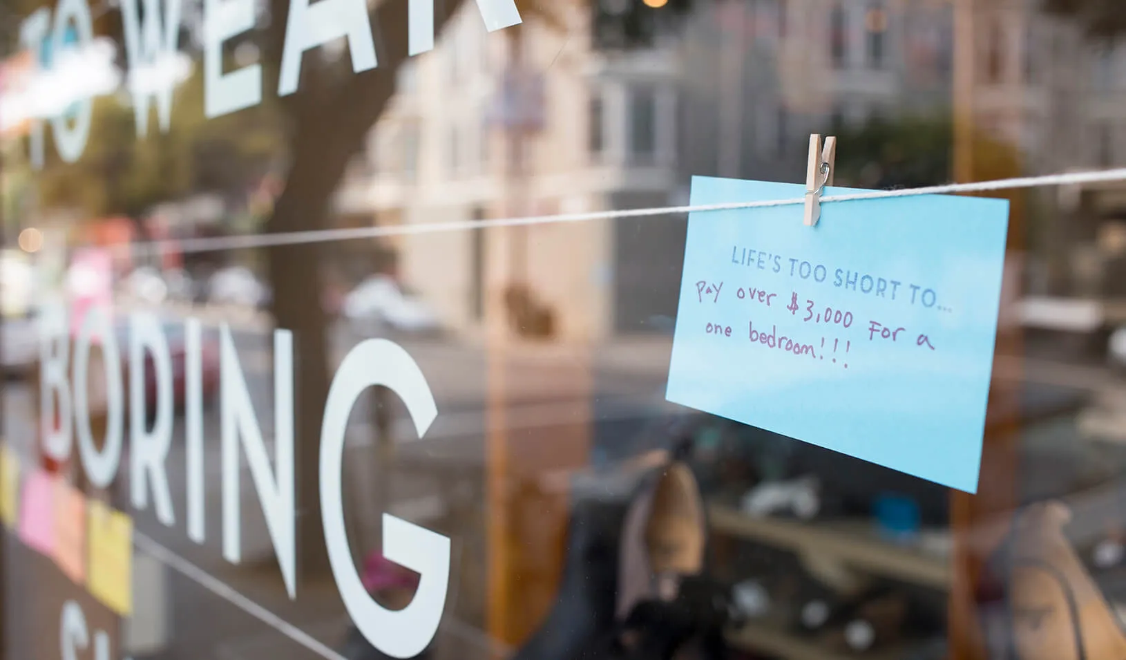 Sign in a window stating "Life's Too Short To Pay Over $3,000 for a bedroom."  | iStock/Fireglo2