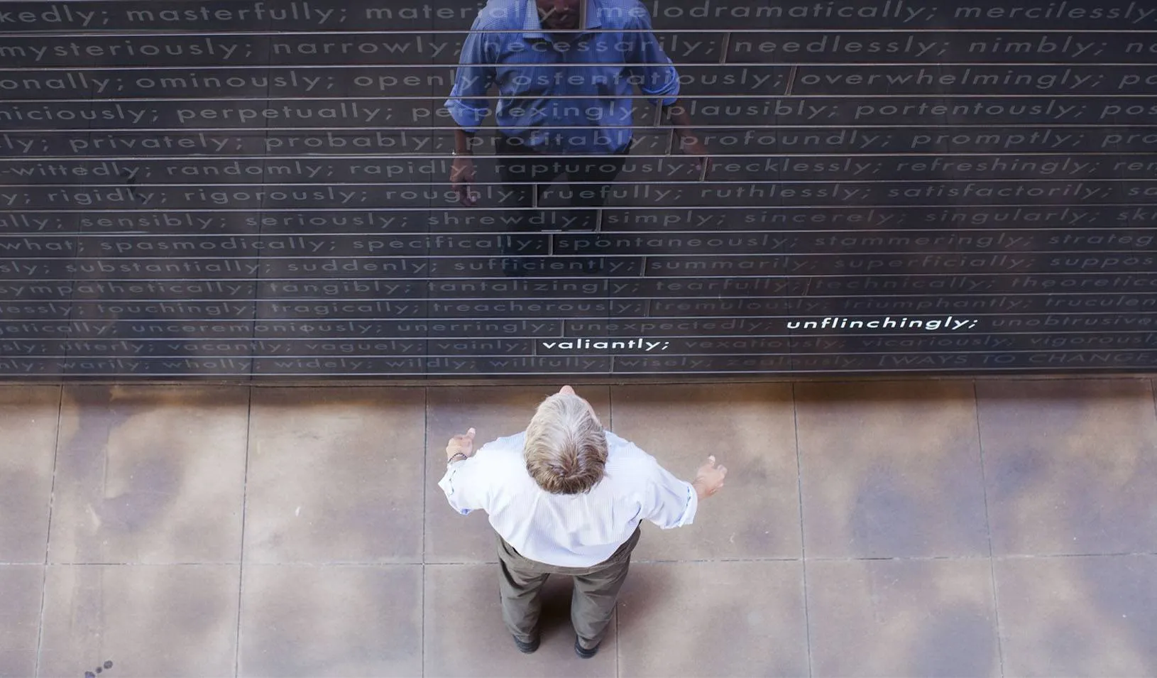  Looking down at a man, who is looking at his reflection in the Adverb Wall at Stanford GSB. Credit: Elena Zhukova