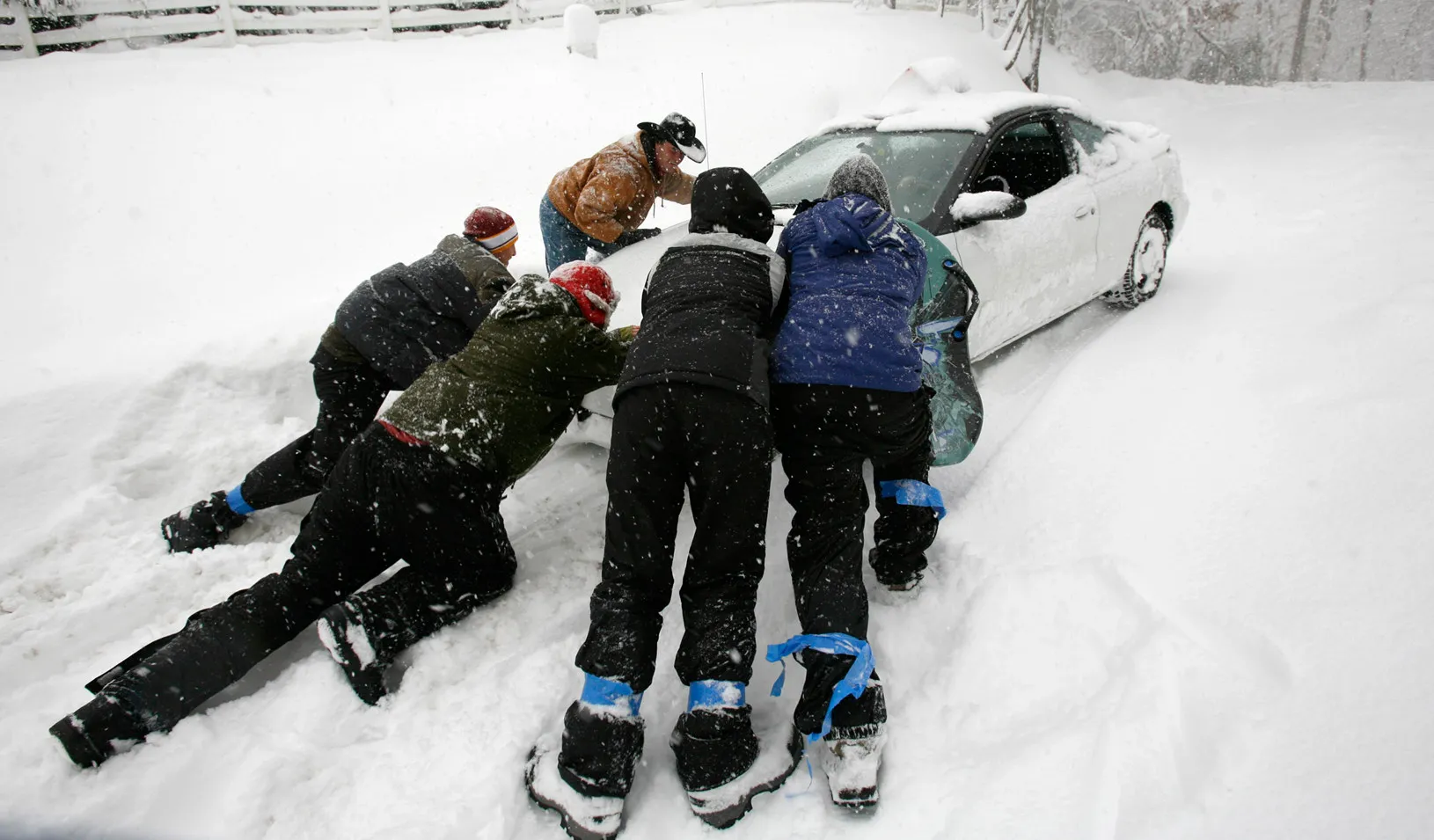 Neighbors push a vehicle out of a snow-covered road, 2010 (Reuters photo by Hyungwon Kang)