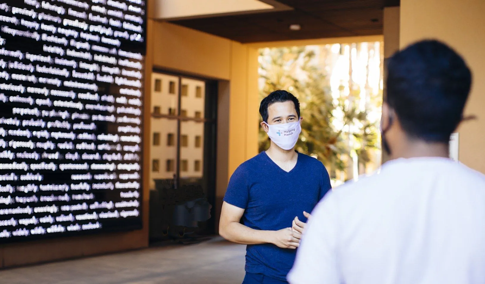 Two students in conversation in front of the Adverb Wall at Stanford