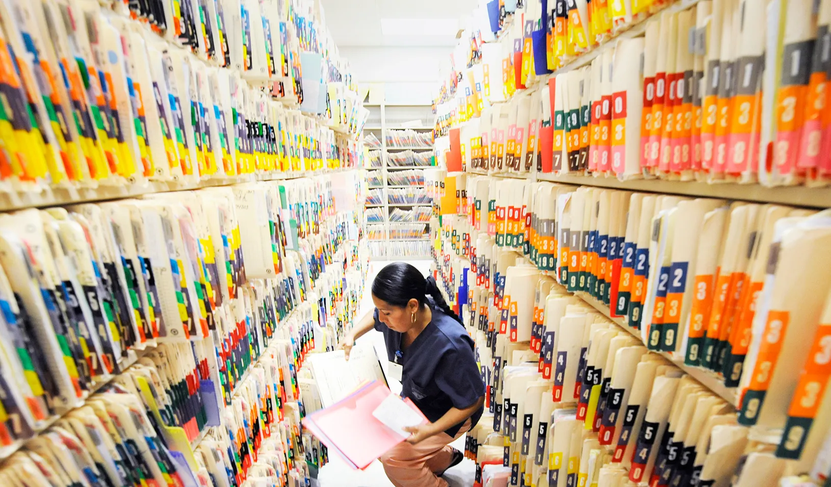 Health care worker reviewing a file in a massive archive | Reuters/Phil McCarten