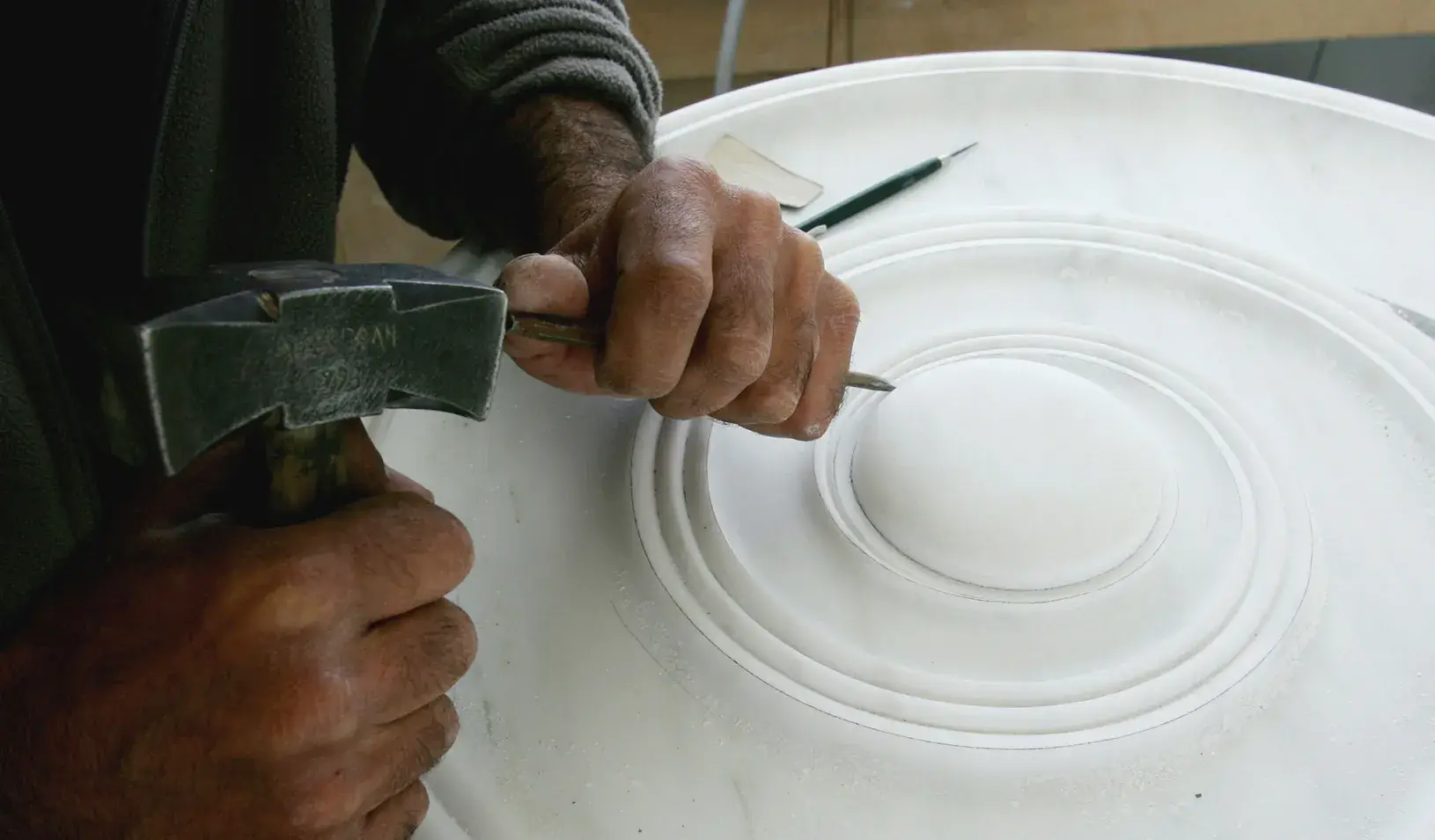 A sculptor works on a piece of marble, trying to create a replica of an Ionic column inside one of the Acropolis' restoration centers in Athens. | Reuters/Yiorgos Karahalis