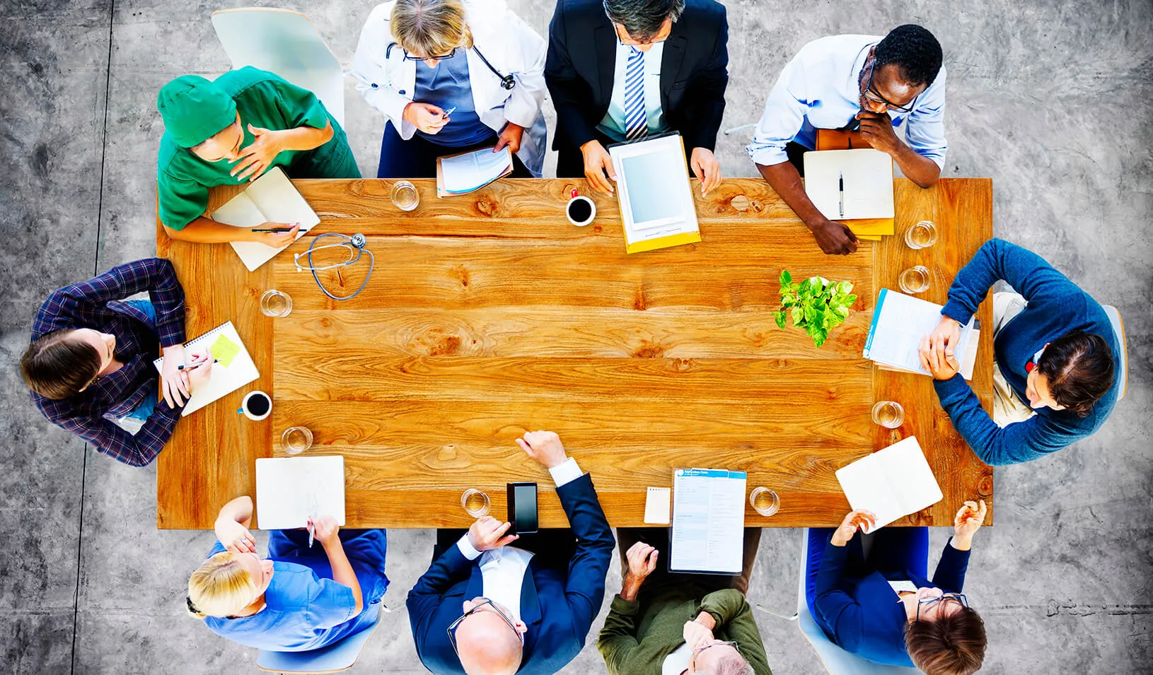 Doctors conduct a meeting around a conference table | iStock/Rawpixel