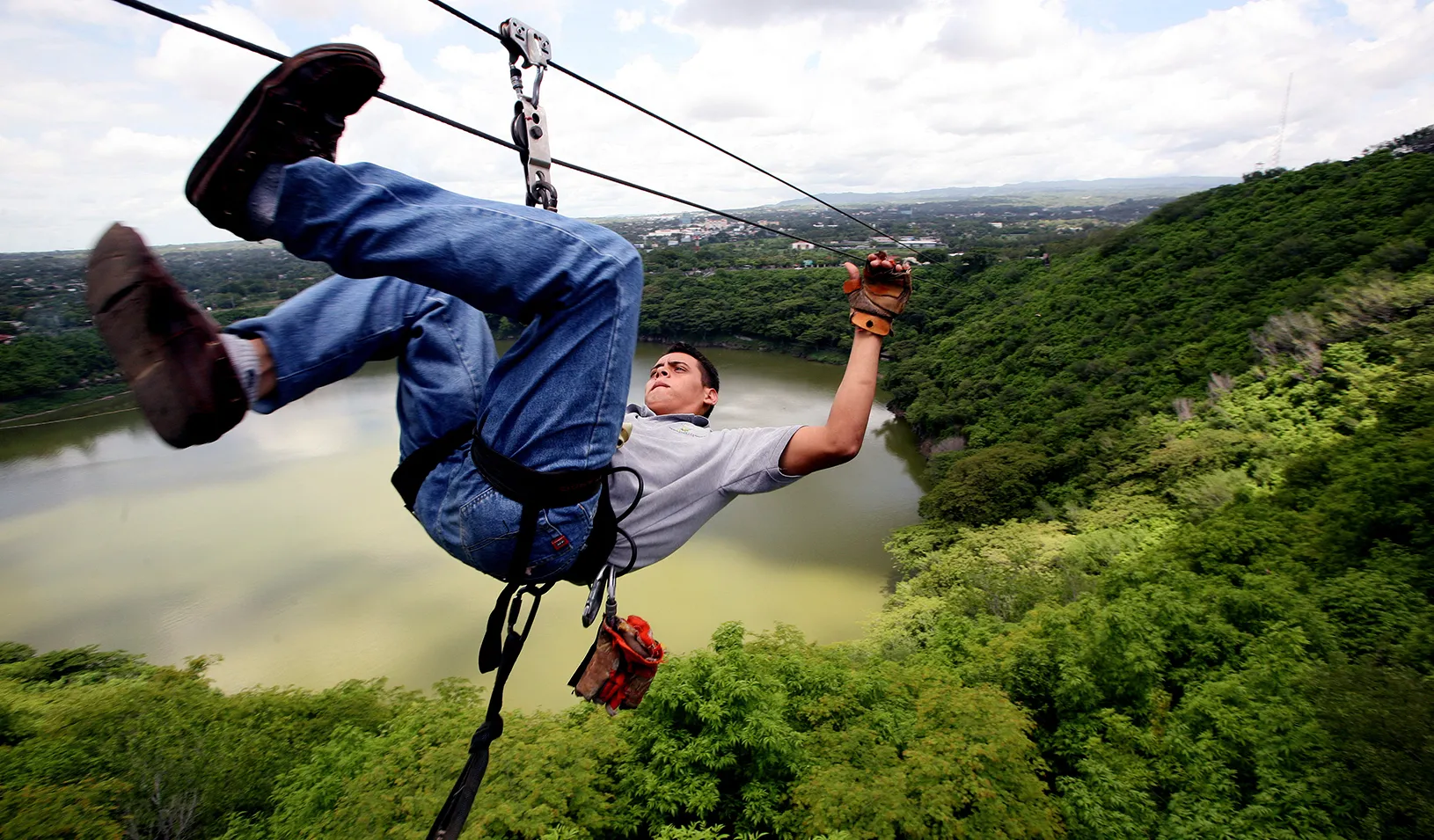Picture of a man zip lining over a forest 
