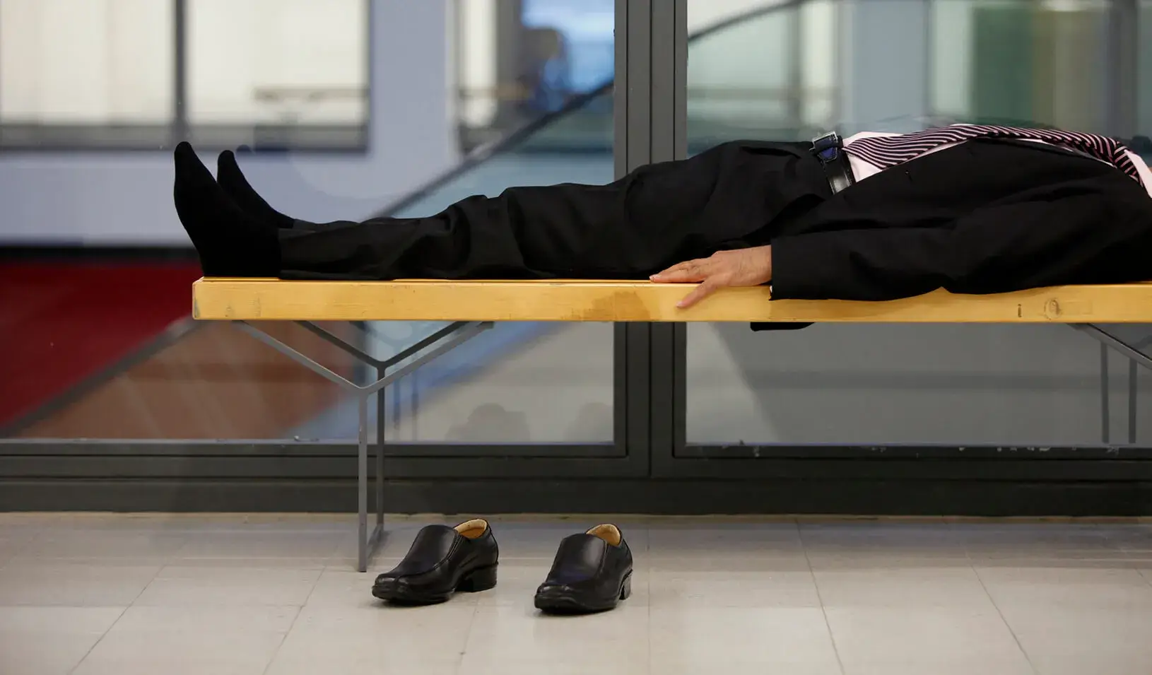 A man lays on a bench. | Reuters/Thomas Peter