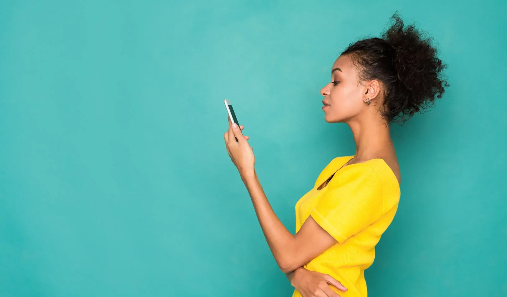 A woman looks at her cell phone | iStock/Milkos
