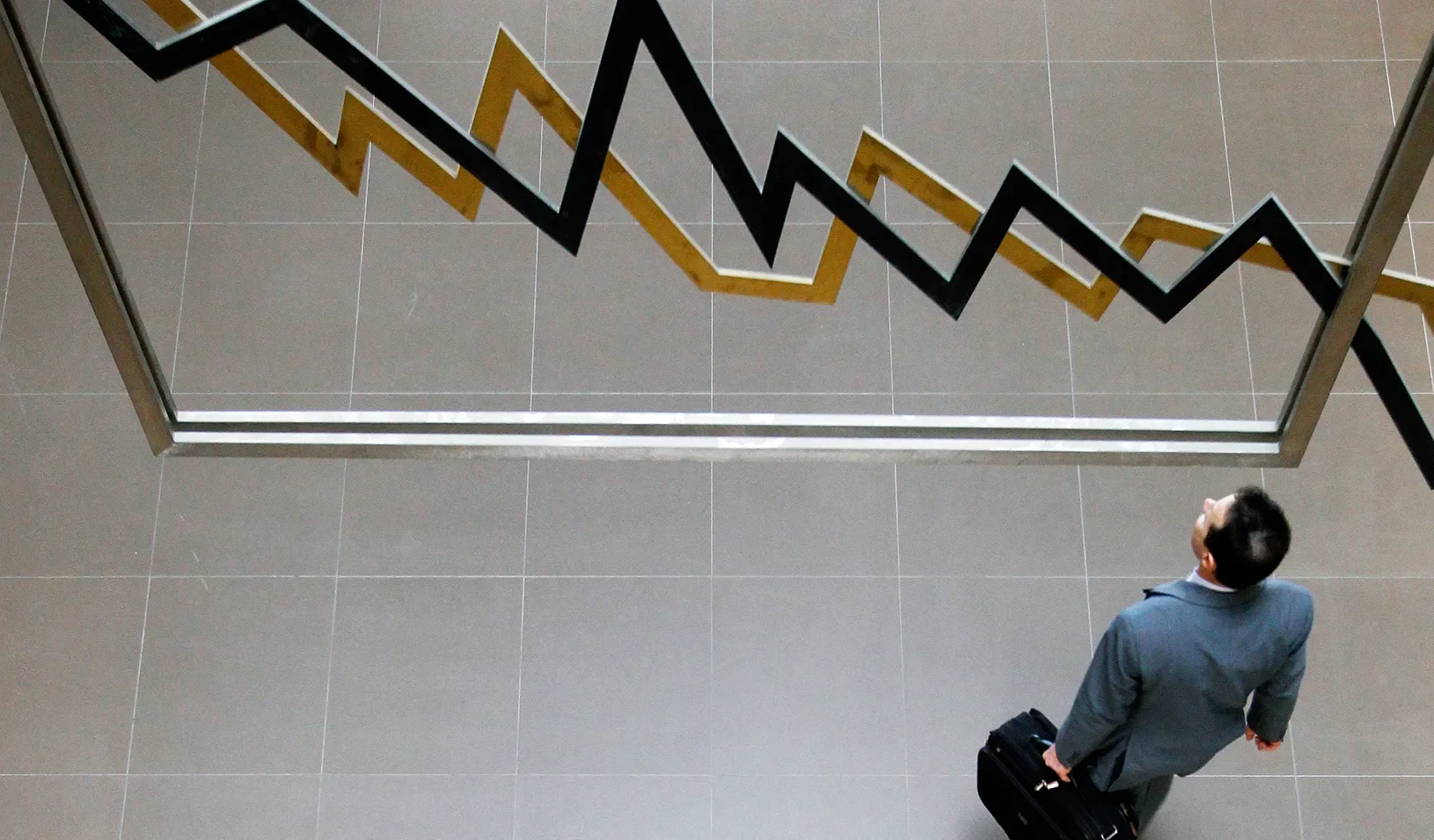 A man standing in front of a chart with a downward trend. | Reuters/Yiorgos Karahalis