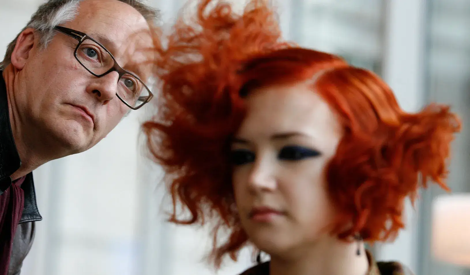 A stylist looks at the hair of his model