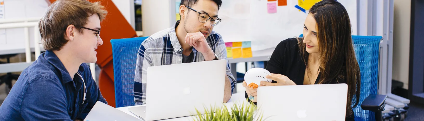 Three young professionals with computers meet about a project 