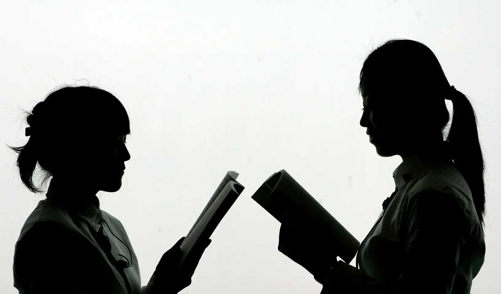 Two women facing each other reading stories