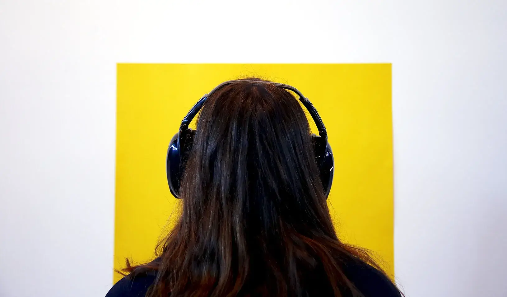 person looking at a yellow square with ear-covering headphones on