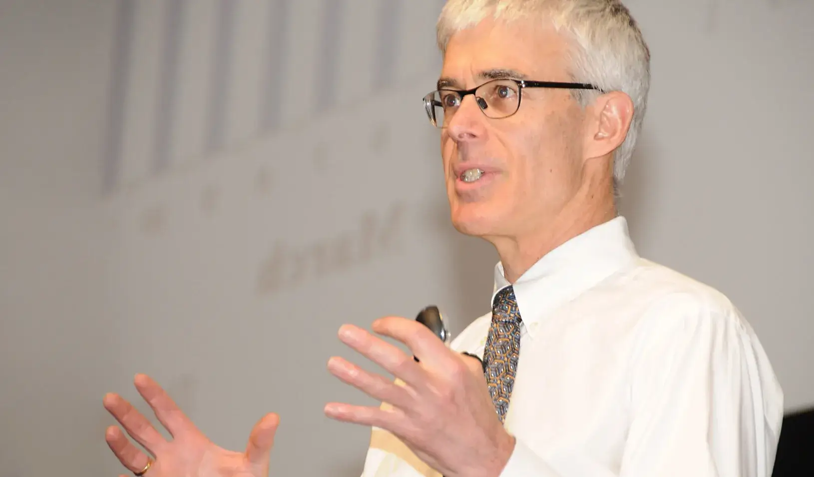 Professor of Management and Professor of Finance Darrell Duffie stands on stage holding up his hands. Credit: Stanford University