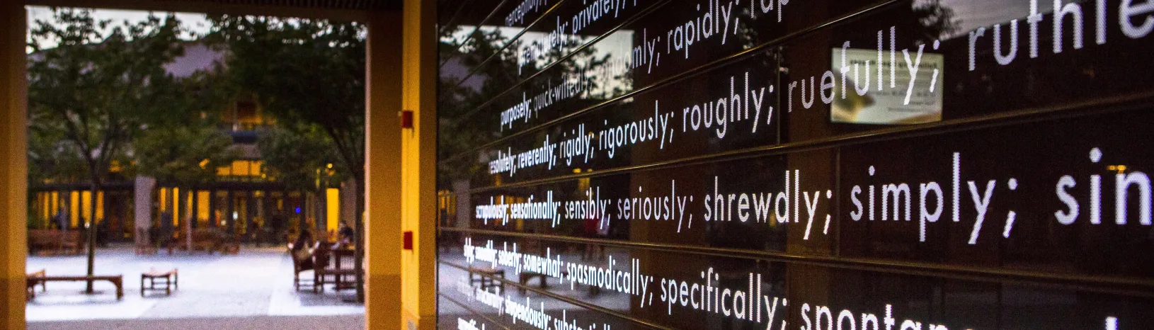 Art installation on campus showing "purposefully" and other adjectives lit up on a black wall