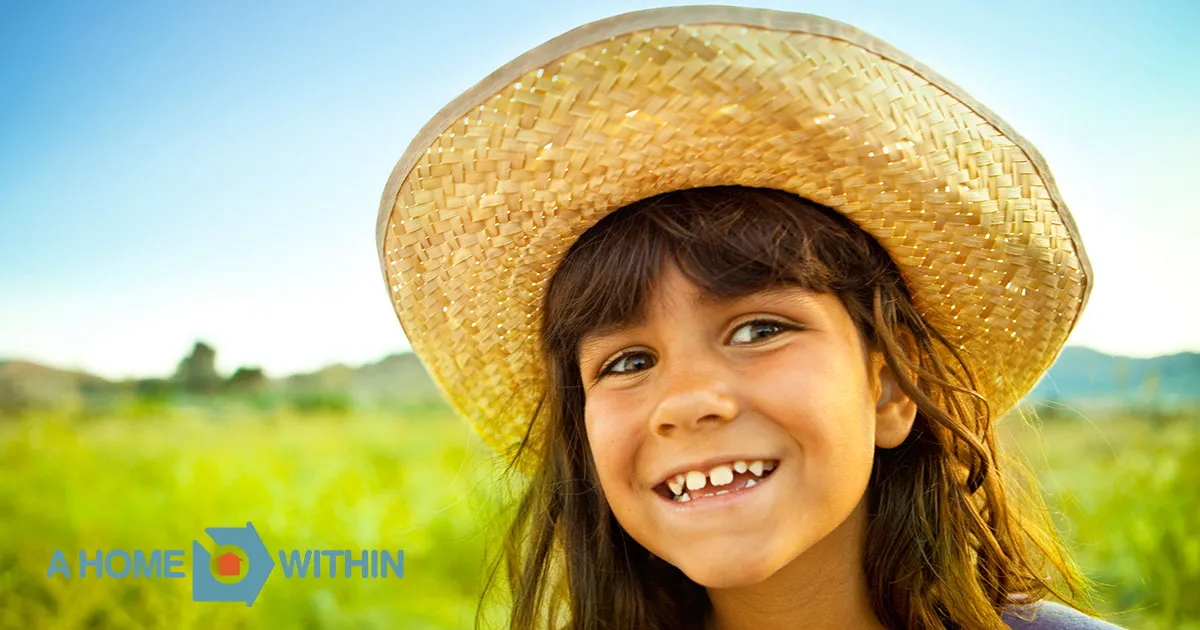 A beaming young girl in straw hat.