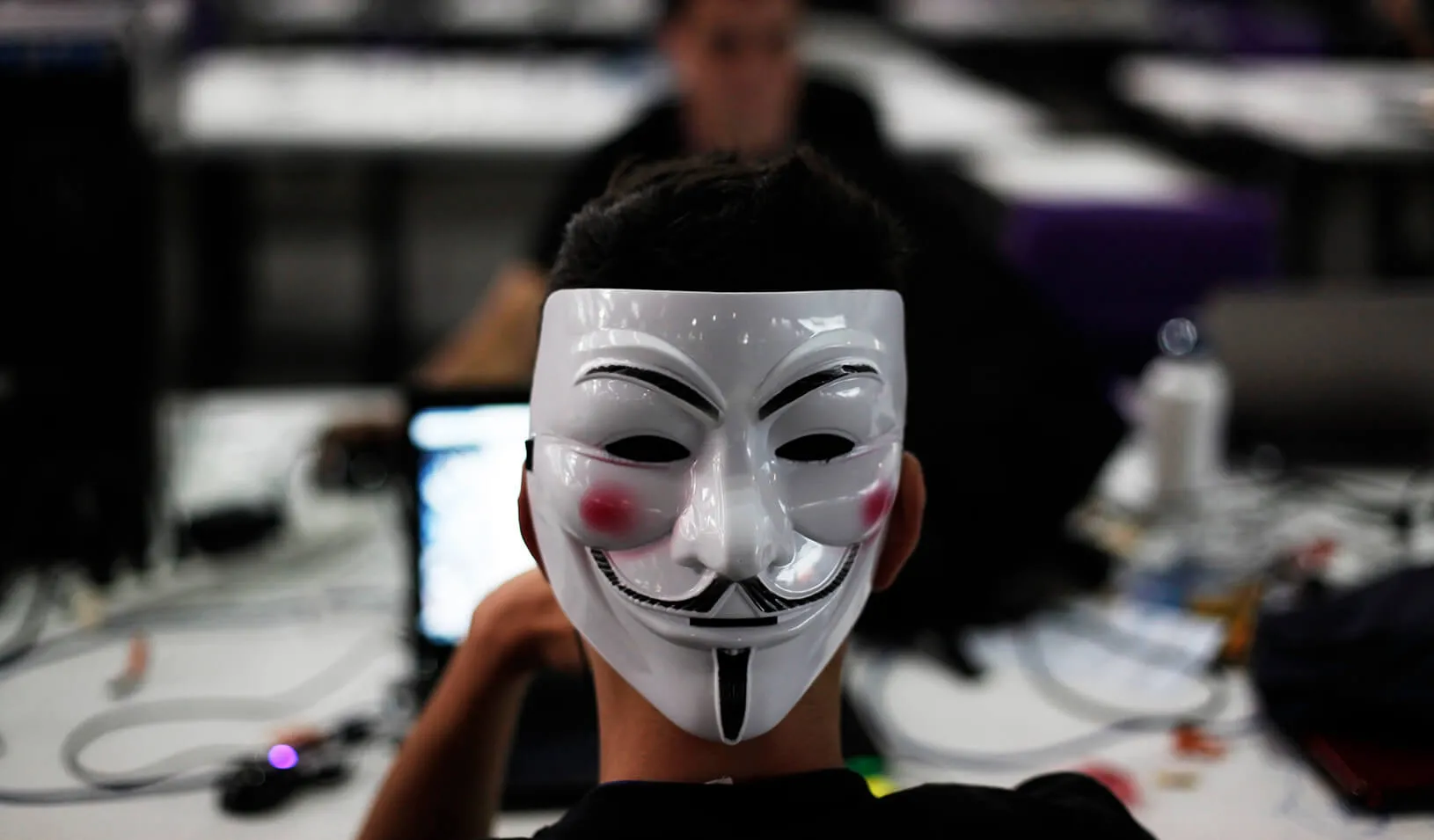 A man wearing a Guy Fawkes mask surfs the web