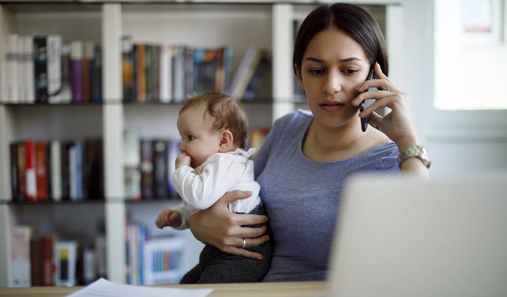 Stressed mother using mobile phone and laptop at home. Credit: iStock/damircudic