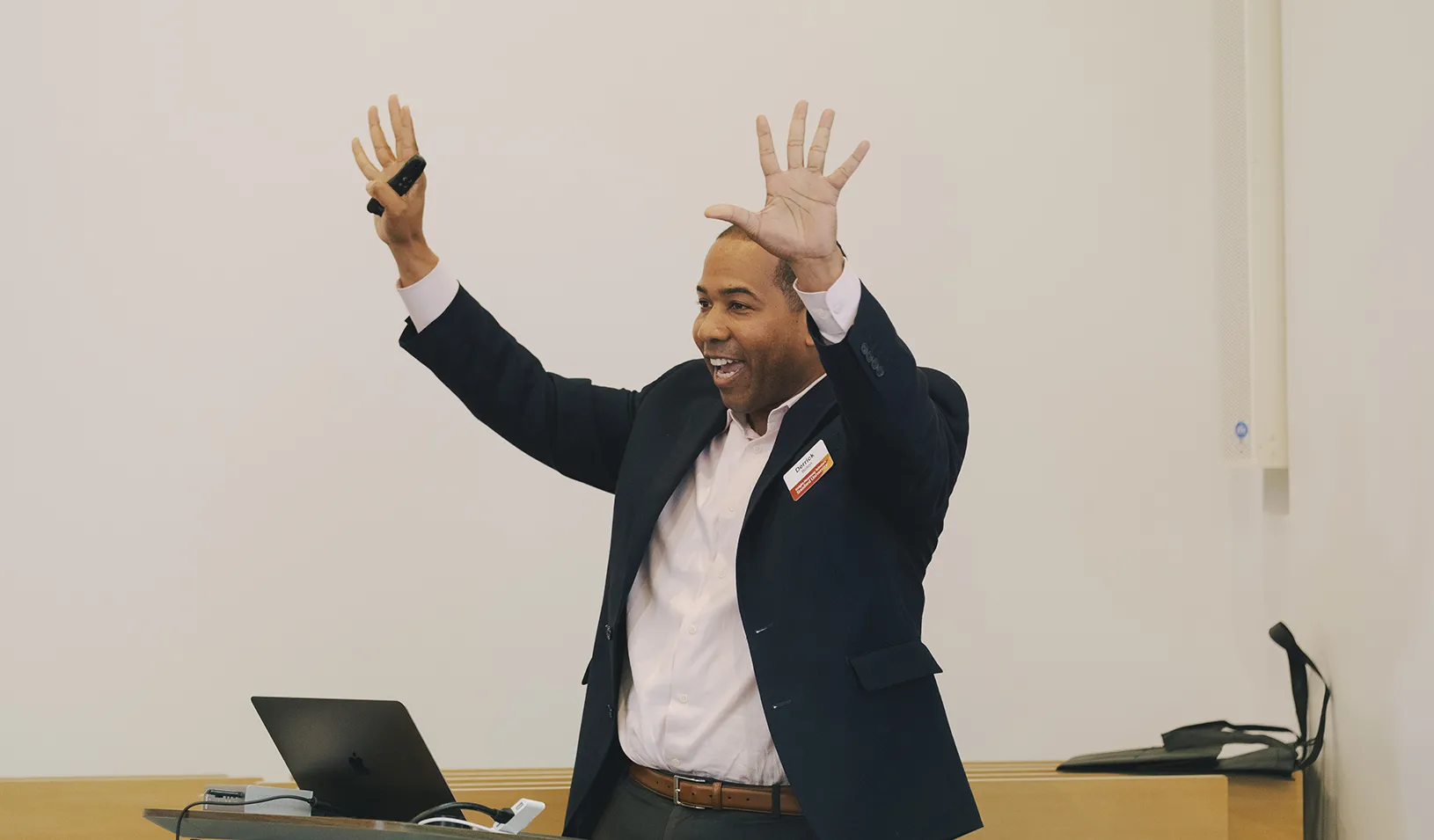Derrick Bolton excitedly raising his hands and standing at a podium while speaking at an event. Credit: Micaela Go