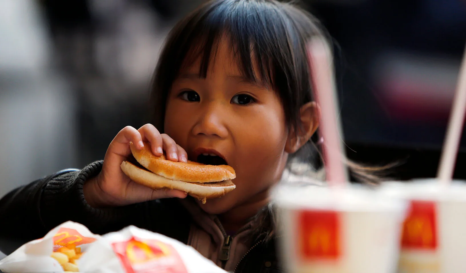 A child eats a hamburger at a fast food restaurant. | Reuters/Stefano Rellandini