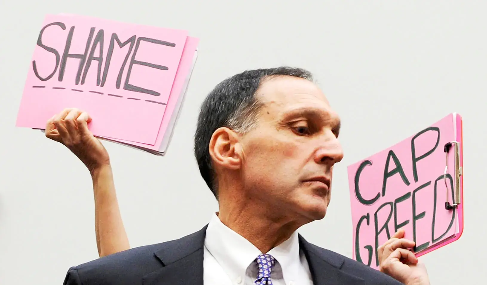 Protestors hold signs behind Richard Fuld, Chairman and Chief Executive of Lehman Brothers Holdings, as he takes his seat to testify at a House Oversight and Government Reform Committee hearing. Credit: Reuters/Jonathan Erns