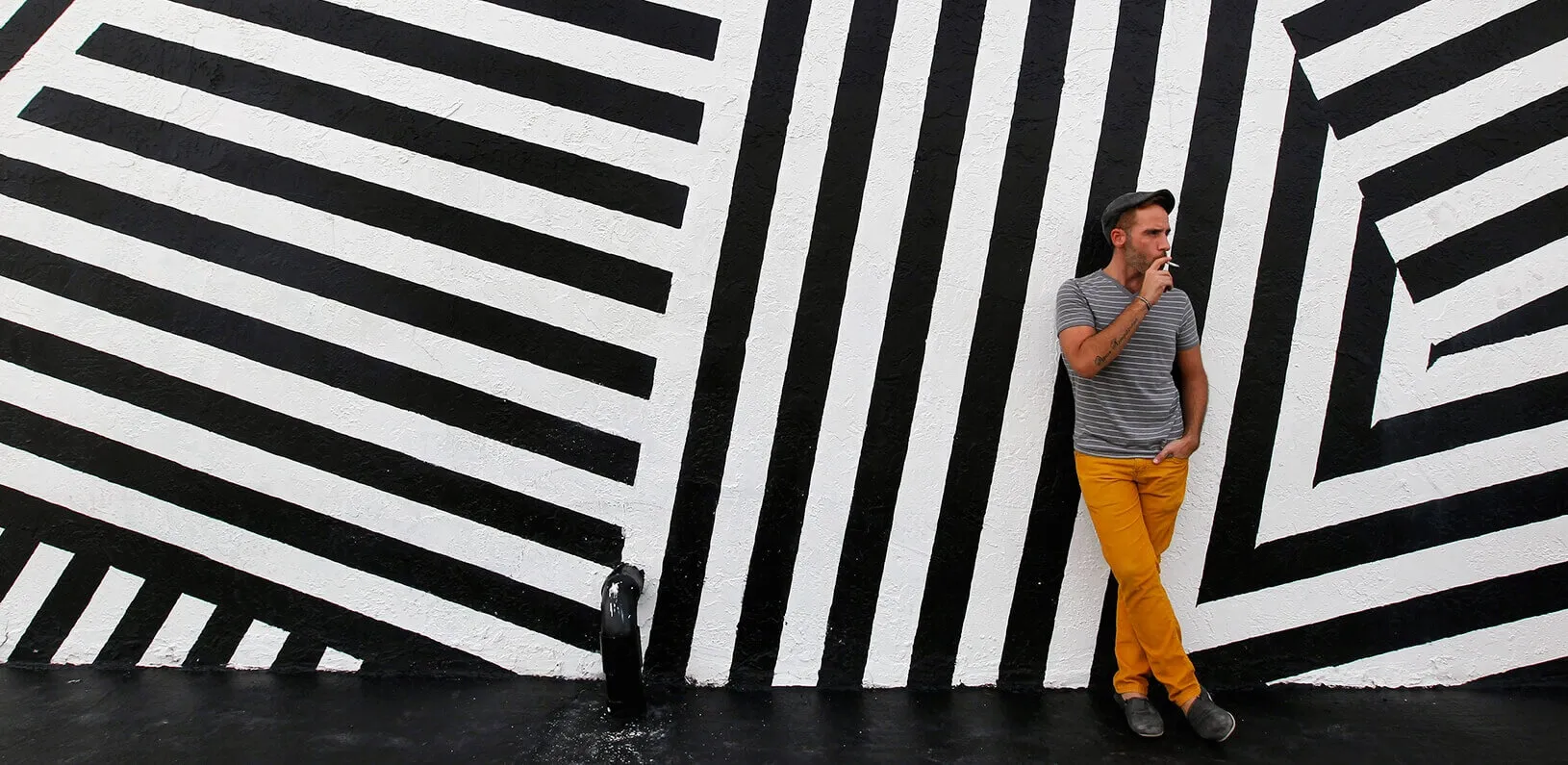 man smoking in front of an art mural