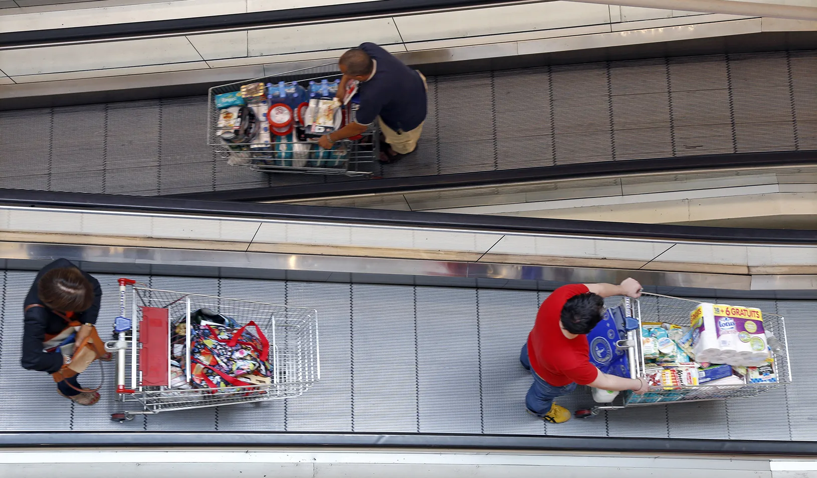 Customers push shopping carts on an escalator. Credit: Reuters/Charles Platiau