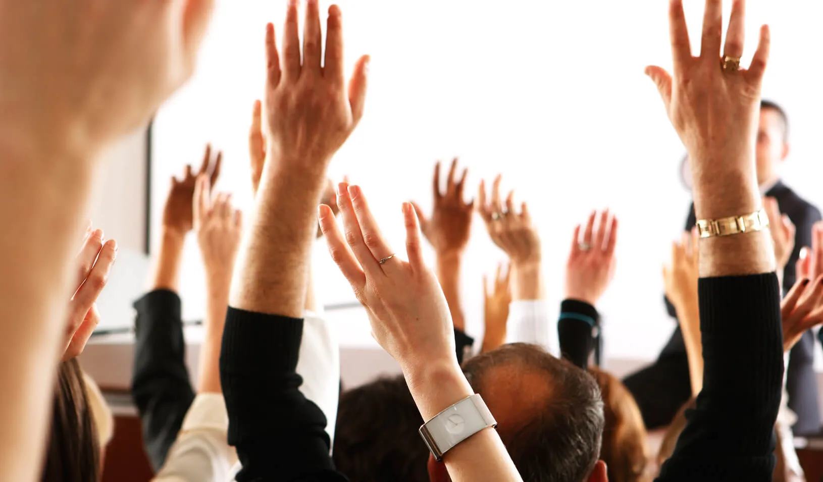 participants in an audience raising their hands