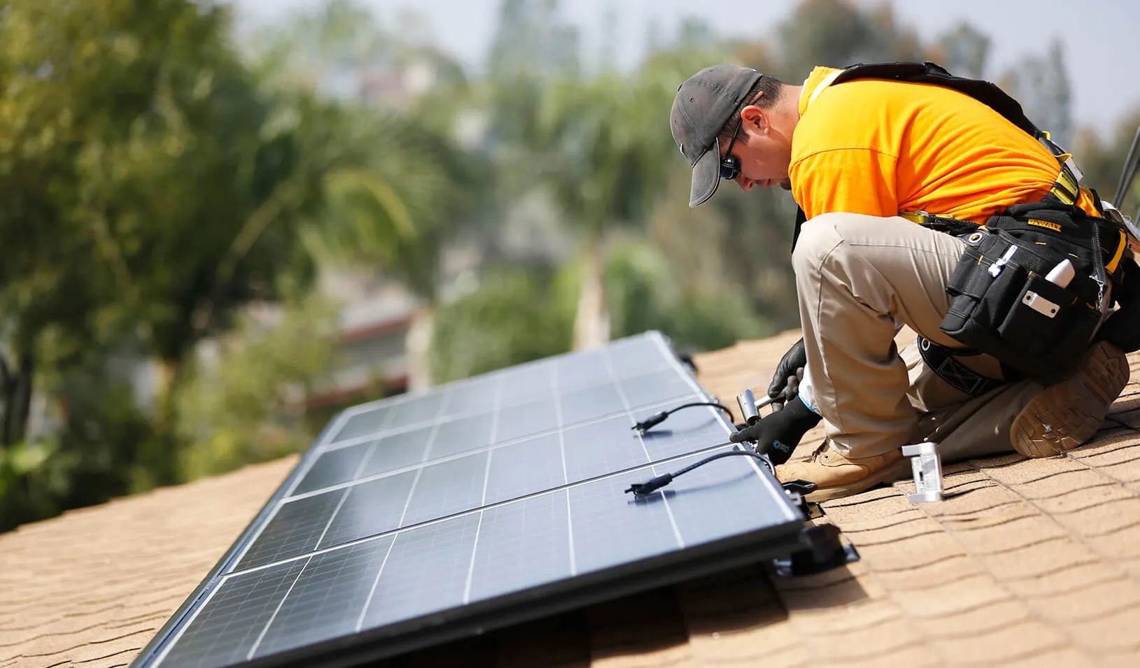 A solar technician installs panels on the roof of a house