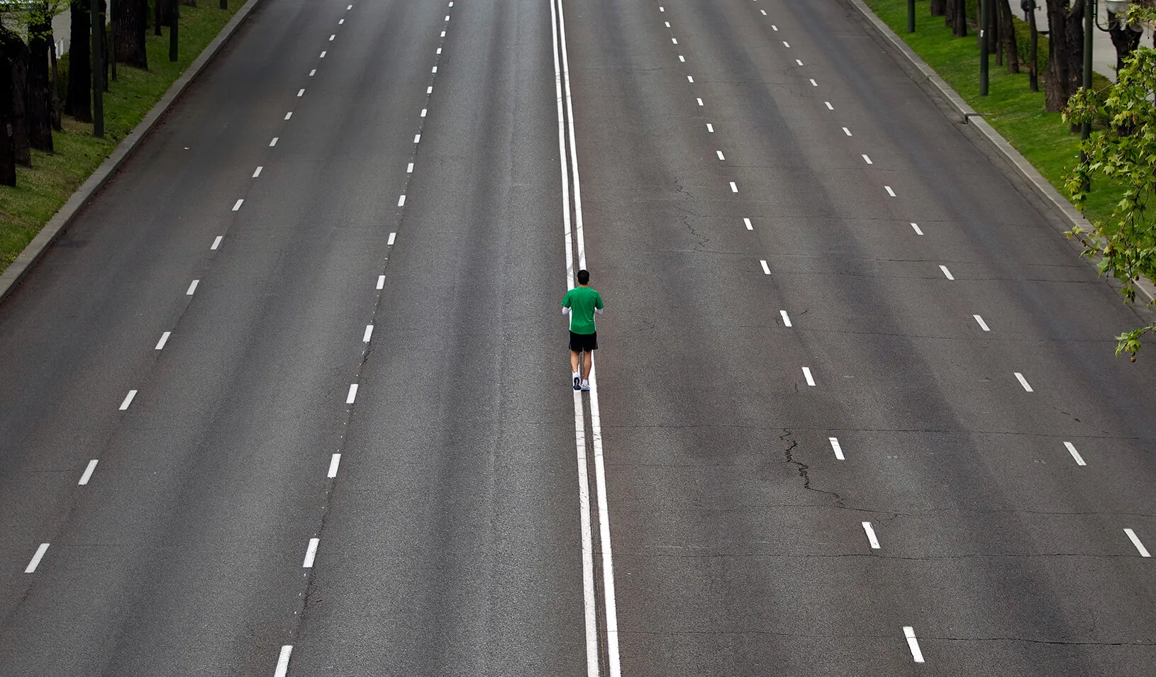 A man standing in the middle of an empty six-lane road