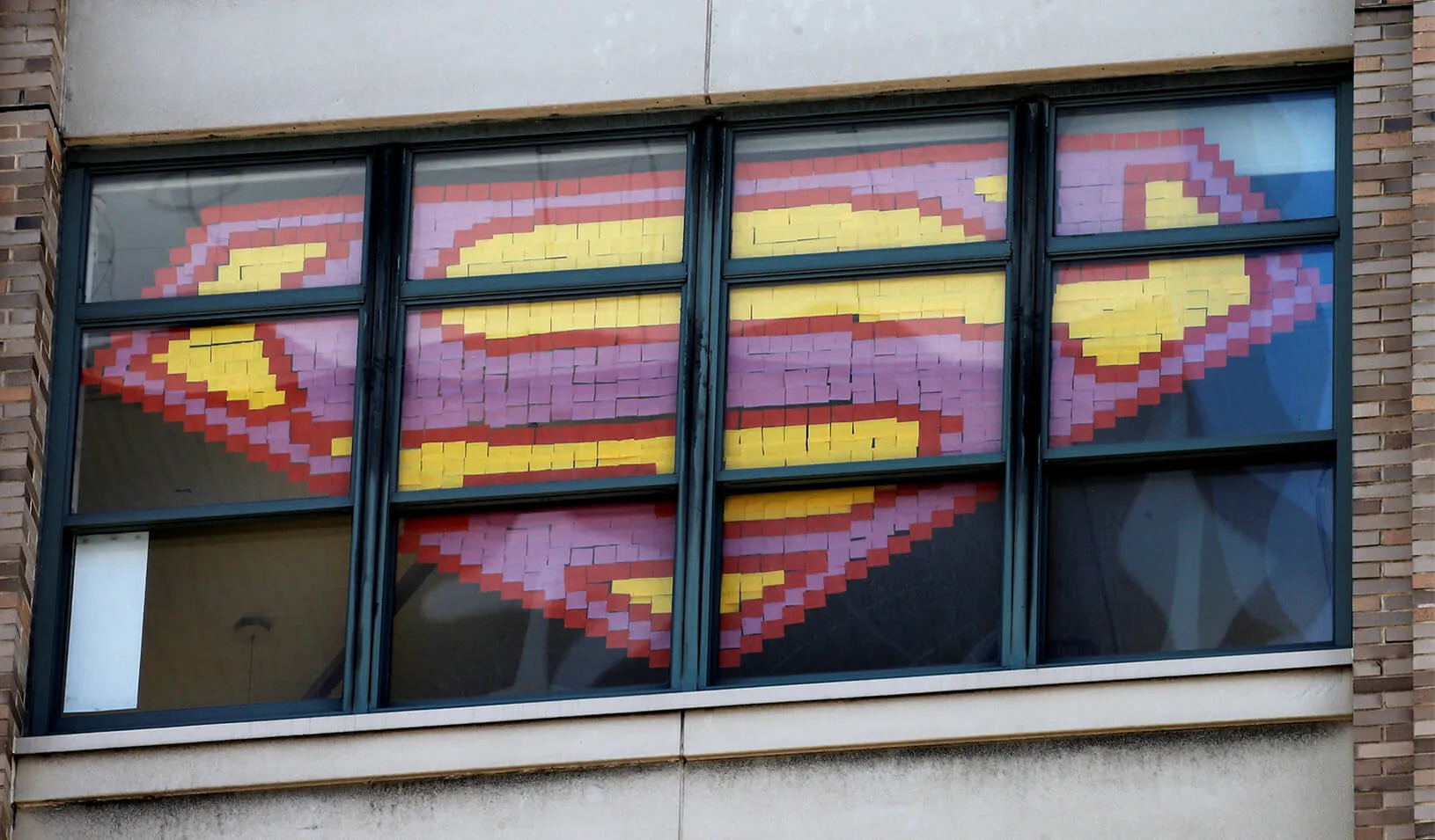 Superman's logo created using sticky notes in a window
