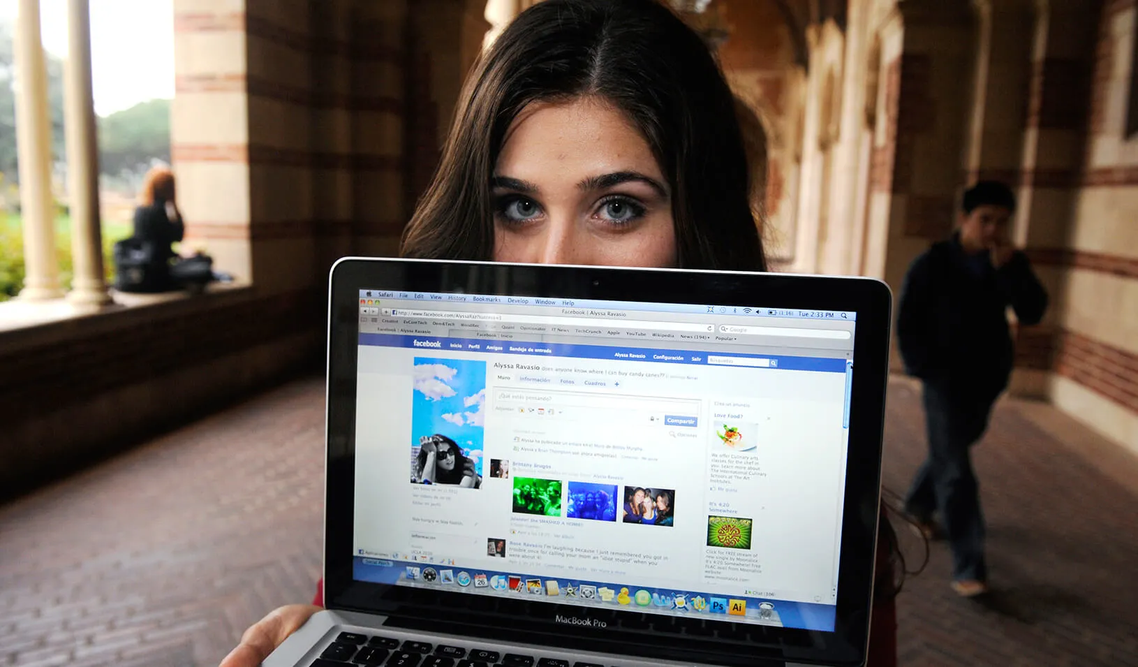 A girl holding a computer that has Facebook on it