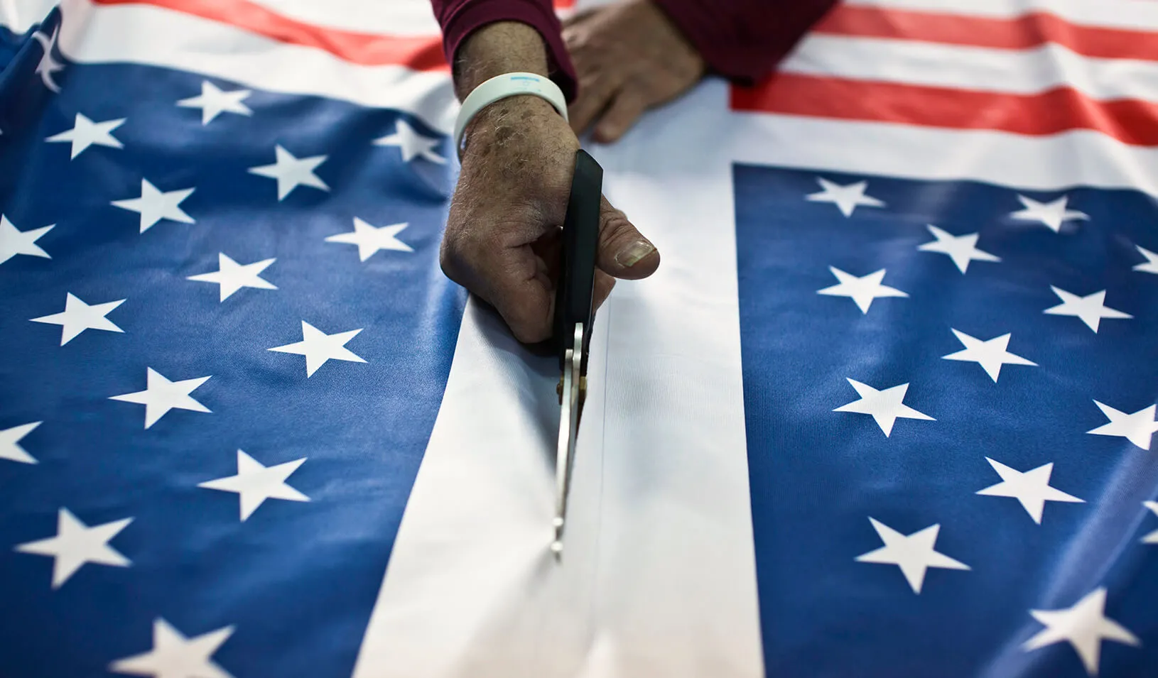 A worker at a factory in Kfar Saba near Tel Aviv cuts fabric printed with U.S. flags. | Reuters/Nir Elias