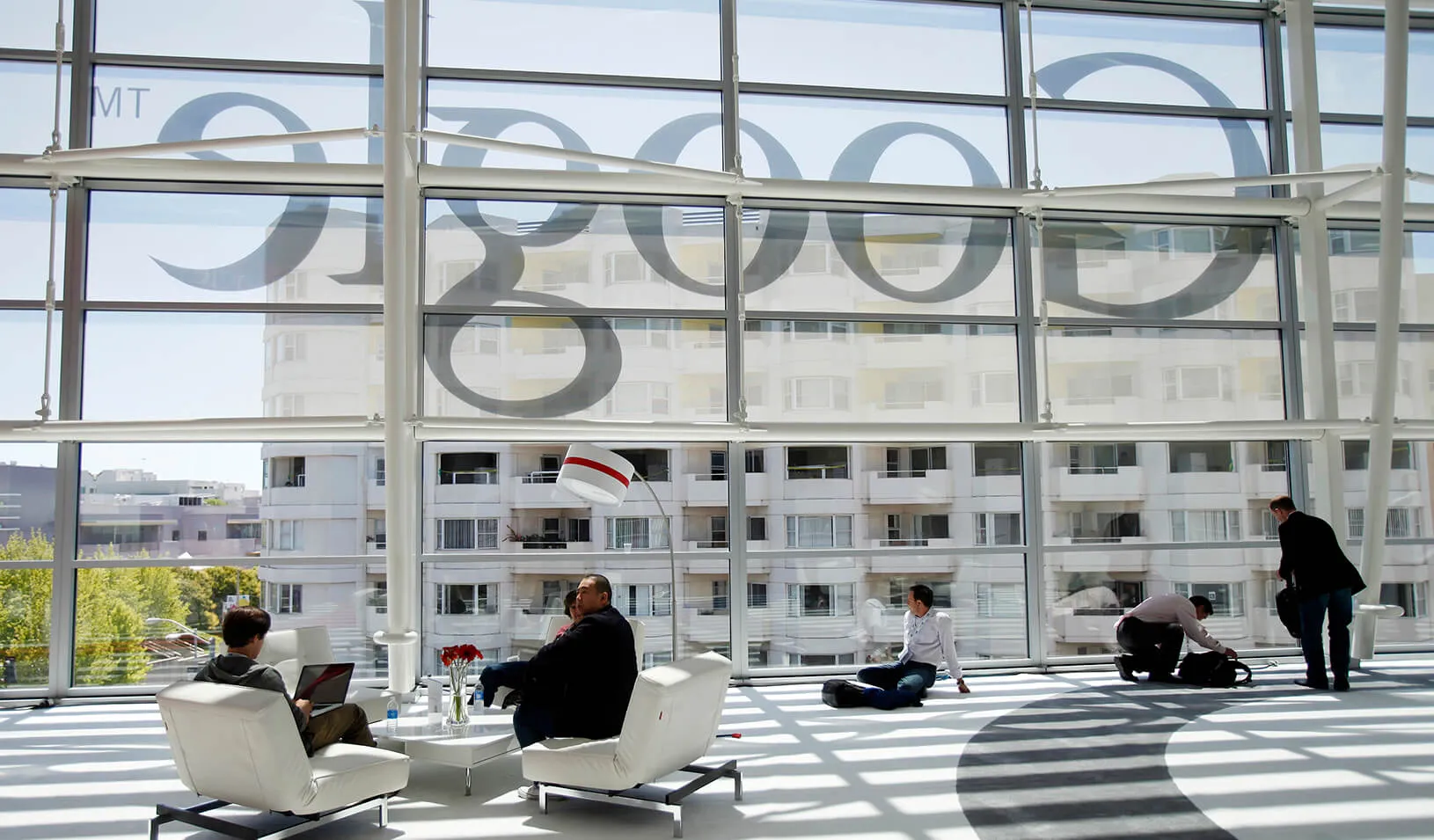 Men shown in the lobby with the Google logo reflected in the background. Credit: Reuters/Stephen Lam
