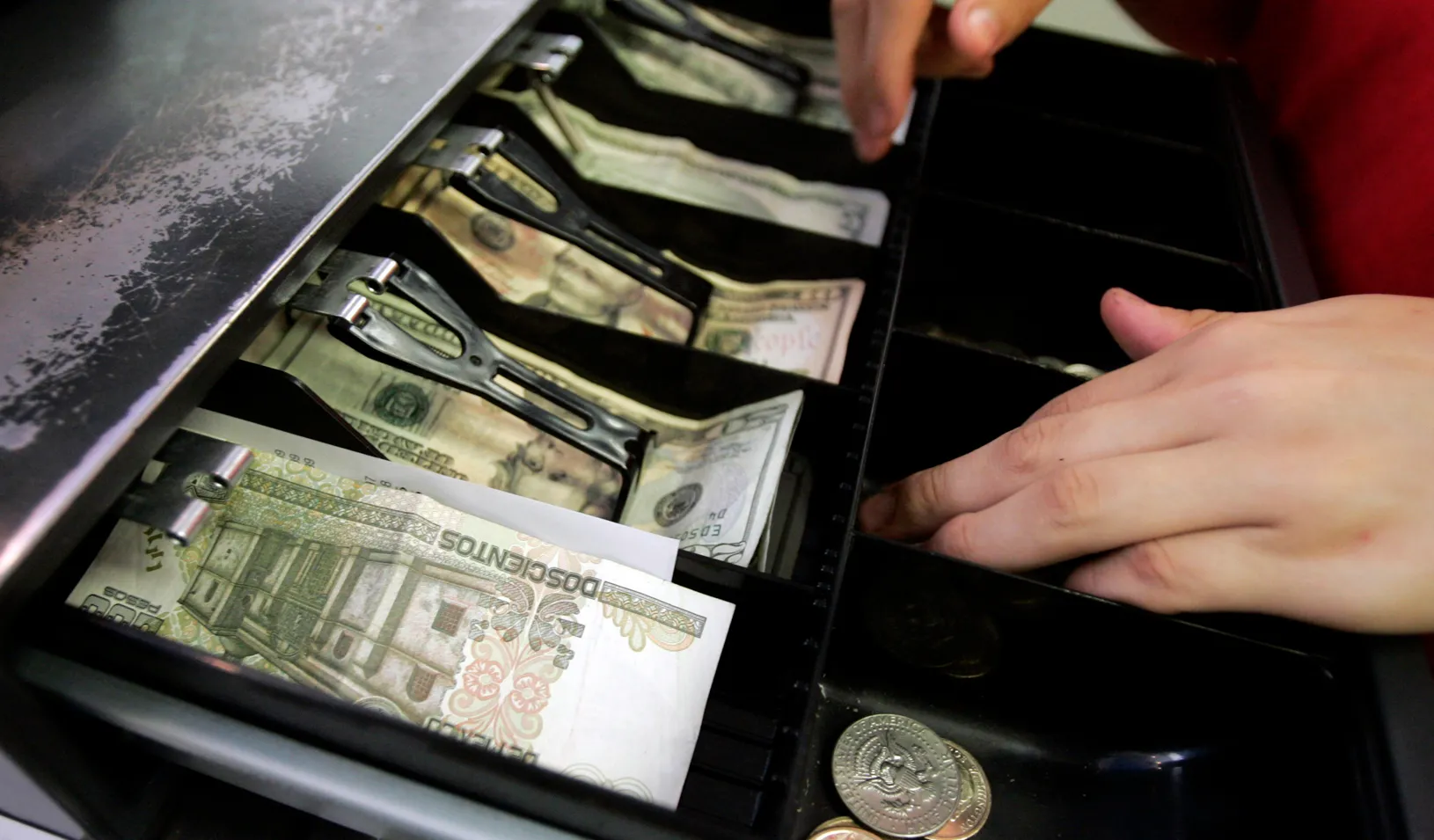 Mexican currency is seen in the cash register drawer alongside U.S. Dollars as a cashier at Pizza Patron makes change for a customer in Dallas, Texas. Credit: Reuters/Jessica Rinaldi