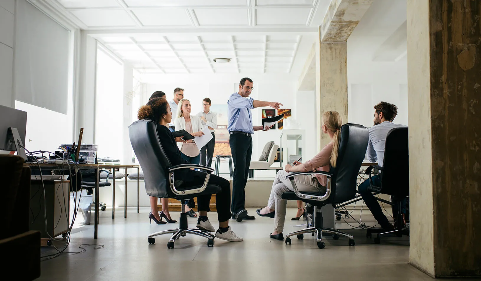 A manager, standing among his employees, points at one of them during a meeting. Credit: iStock/Thomas_EyeDesign