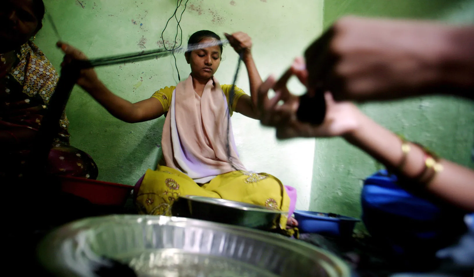 A customer of a micro finance institution strings beads into necklaces at a workshop in a slum area in Mumbai February 17, 2007