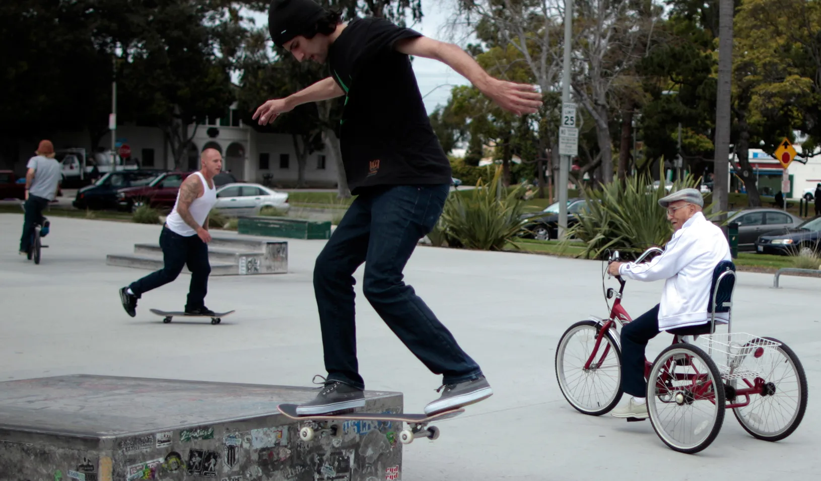 Young guys on skateboards and an older man on a bike
